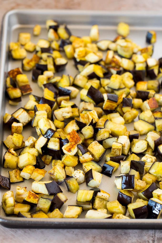 This caponata recipe is a sweet and savory blend of eggplant, peppers, tomatoes and olives, all simmered together to create a delicious appetizer. Roasted eggplant on a sheet pan.