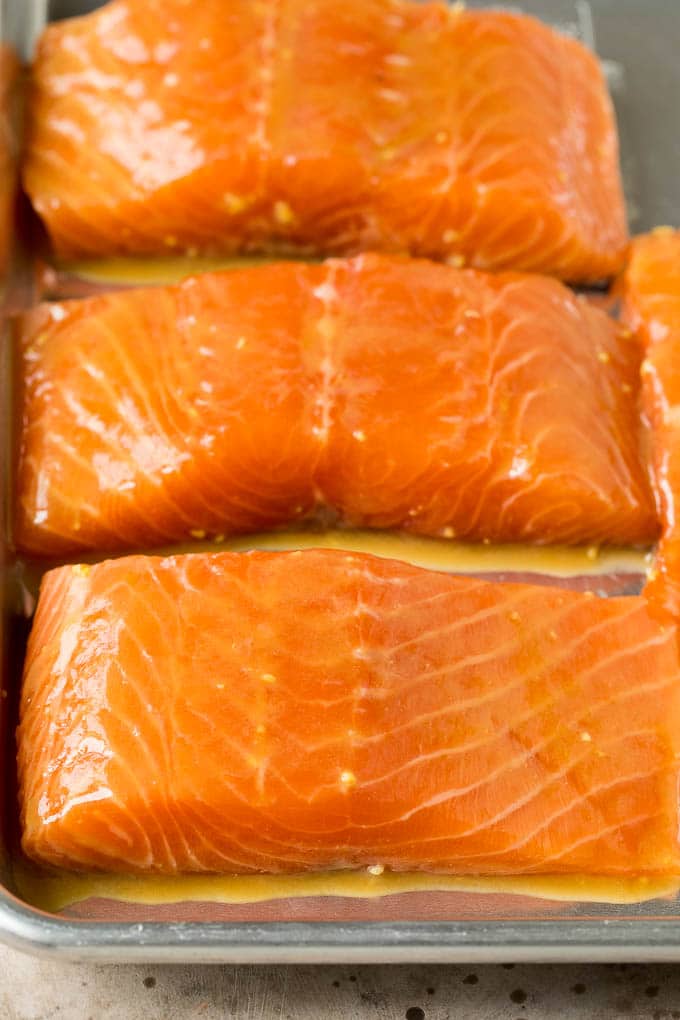 This miso salmon is fresh fish fillets soaked in a flavorful marinade, then broiled to perfection and topped with sesame seeds. Marinated salmon pieces on a sheet pan.