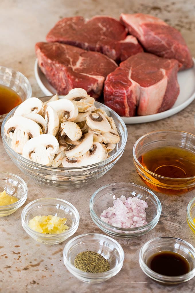 This Steak Diane recipe is beef tenderloin medallions that are seared and coated in a savory mushroom sauce. Bowls of ingredients including sliced mushrooms, shallots, garlic and seasonings.