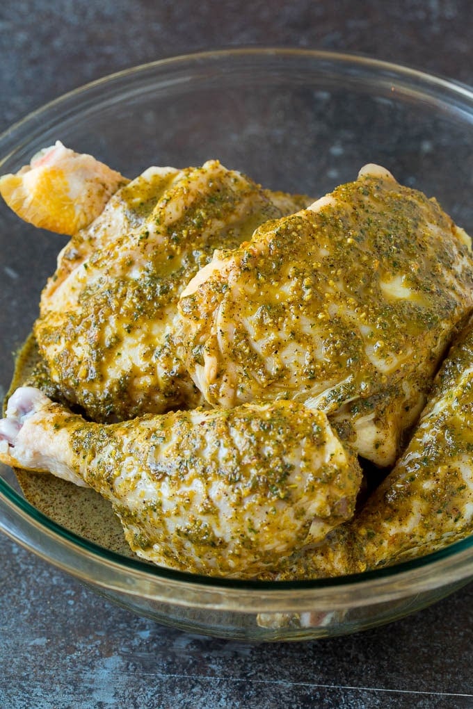 Raw chicken coated in a marinade in a bowl.