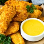 A bowl of honey mustard sauce served with chicken fingers.