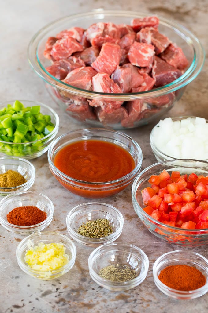 This Mexican style carne guisada is beef that is stewed with tomatoes, peppers and spices until it becomes tender and flavorful. Bowls of ingredients including cubed beef, vegetables and seasonings.