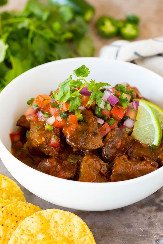 This Mexican style carne guisada is beef that is stewed with tomatoes, peppers and spices until it becomes tender and flavorful. A bowl of carne guisada topped with pico de gallo.