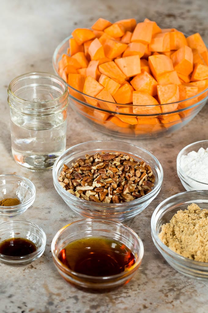 This crock pot sweet potato casserole is yams mashed with sweetener, vanilla and spices, then finished off with a brown sugar pecan topping. Bowls of sweet potatoes, brown sugar, spices and pecans.