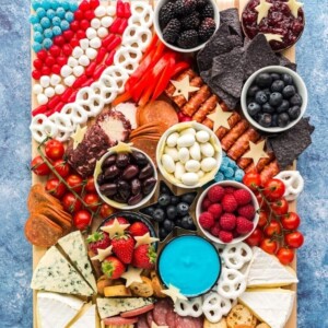 An image of a charcuterie board with cheeses, chips, fruits and veggies.