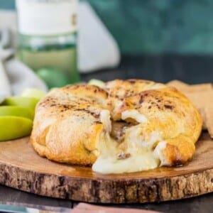 A picture of an apple pie baked brie on a wooden board.