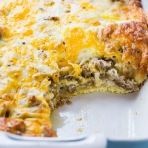 An image of a sausage and crescent roll casserole in a baking dish with a scoop removed.