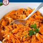 This crock pot buffalo chicken is chicken breasts cooked to tender perfection in a mixture of hot sauce, ranch seasoning and butter.
