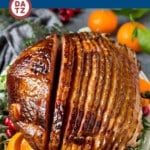 A platter with baked ham which is ham is coated in a homemade brown sugar glaze, then cooked until golden brown and caramelized.