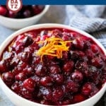 A bowl of cranberry orange sauce with and orange peel garnish.