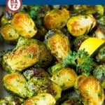 A sheet pan full of crispy brussels sprouts garnished with parsley.