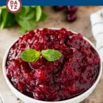 A bowl of slow cooker cranberry sauce garnished with mint and orange slices.