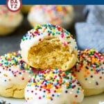 A stack of Italian cookies with glaze and sprinkles on a plate.