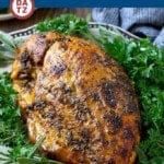 A slow cooker turkey breast on a platter garnished with herbs.