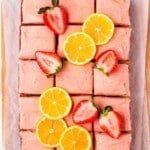 A strawberry lemon cake cut into squares and garnished with fresh berries and lemon slices.