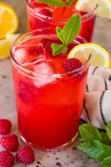 A glass of raspberry lemonade garnished with berries and a lemon slice.