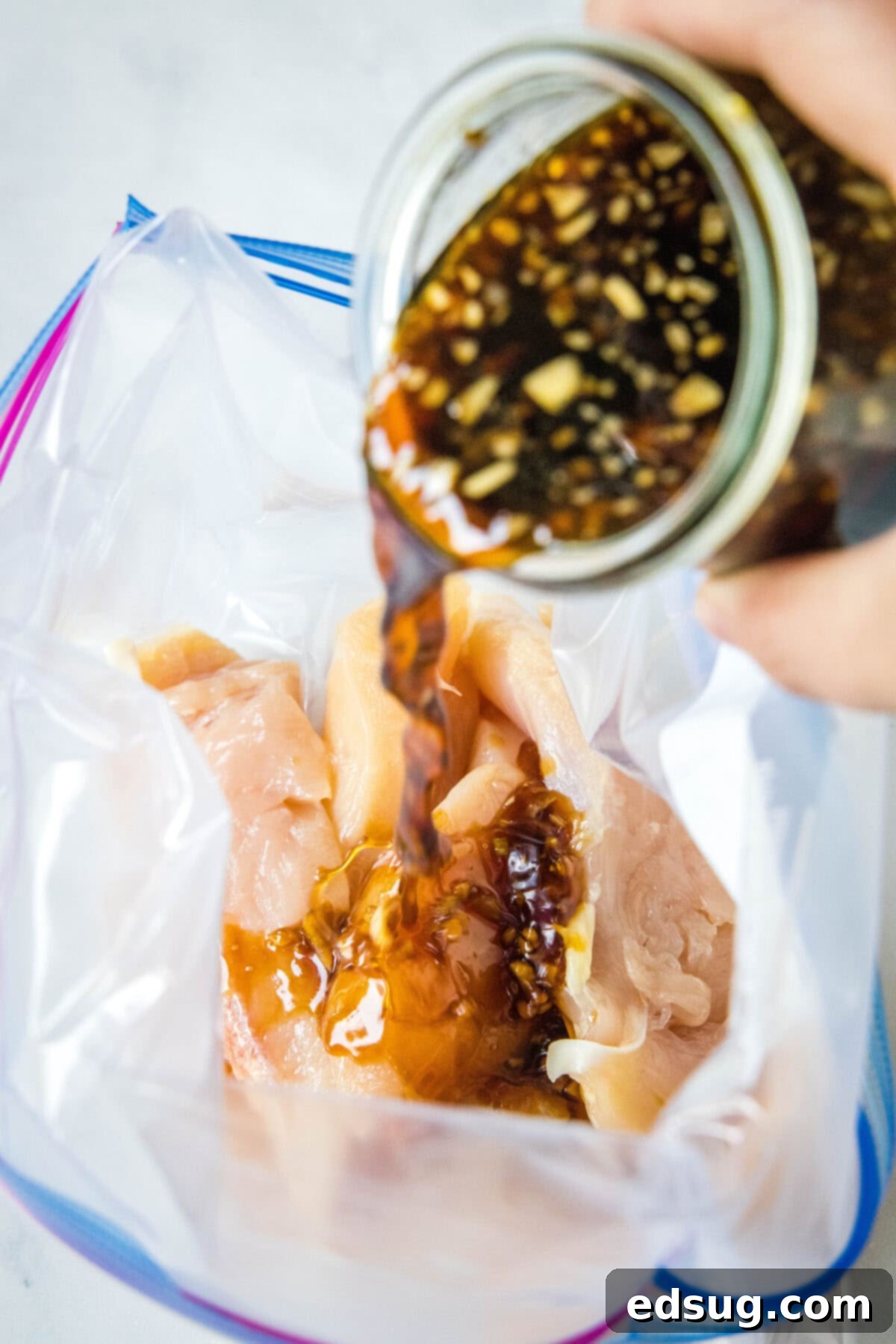 Pouring homemade teriyaki marinade into a bag with chicken pieces to marinate.