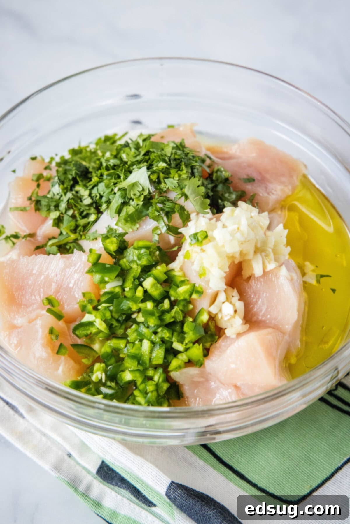 Chicken added to a bowl of cilantro lime marinade.