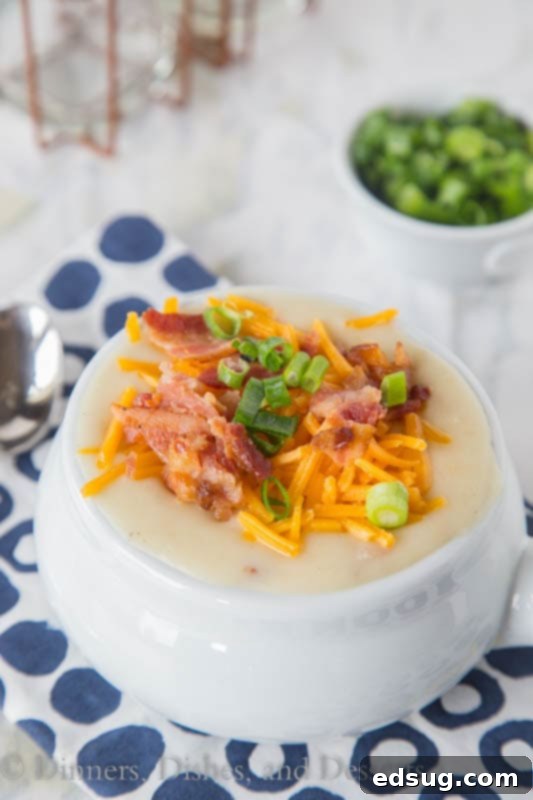 Creamy crockpot potato soup in a bowl with bacon, cheese, and green onions