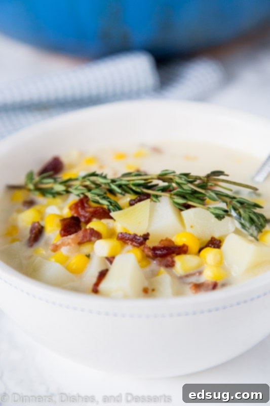 A beautifully presented bowl of creamy potato corn chowder, garnished with fresh herbs and a sprinkle of bacon.