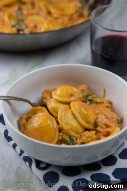 Close-up of creamy Italian sausage and tomato ravioli in a white bowl, garnished with fresh parsley.