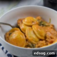 creamy sausage and tomato ravioli in a bowl, garnished with herbs