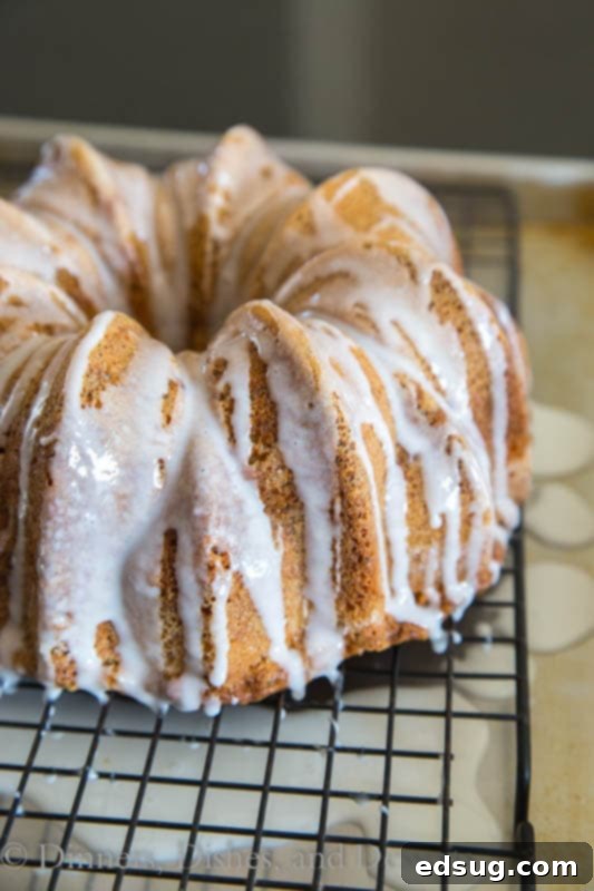 A large slice of Poppy Seed Cake on a white plate, revealing its delicate crumb and the glistening almond glaze.