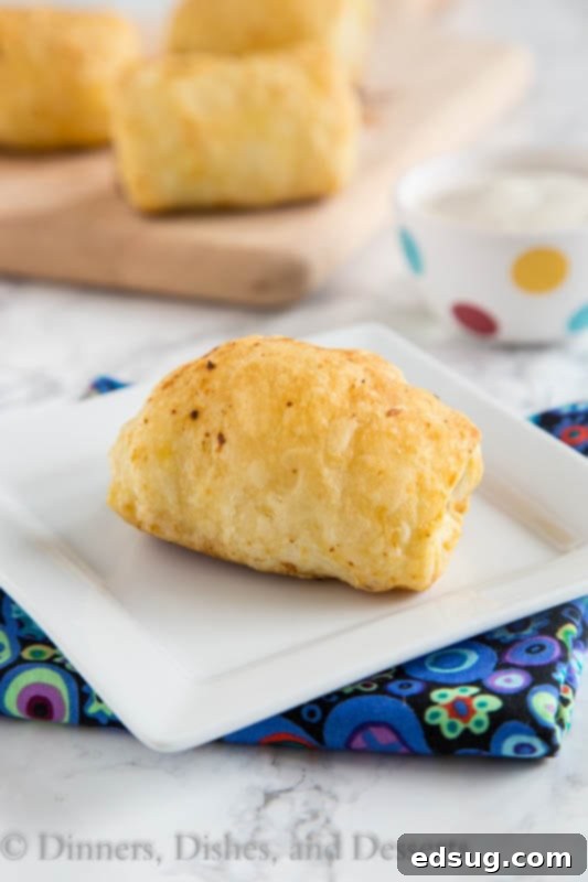 Freshly baked spicy sausage rolls with flaky crust on a baking sheet