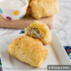 Close up of a single spicy sausage roll, showing flaky pastry and filling