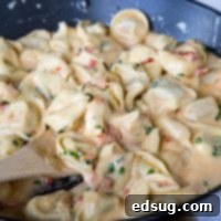 Tomato-Basil Tortellini in a bowl, garnished with fresh basil