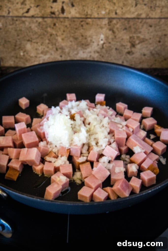 Seasonings added to sauteed ham and onions in a skillet.