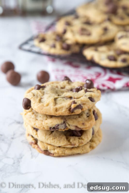Whopper Candy Malted Chocolate Chip Cookies 4 A stack of golden-brown Malt Chocolate Chip Whopper Cookies on a white napkin, highlighting their inviting texture and delicious appearance.