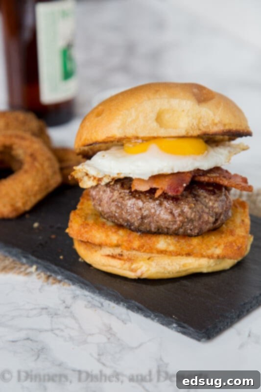 A glorious breakfast burger with a runny fried egg, bacon, and hash browns, served on a plate.