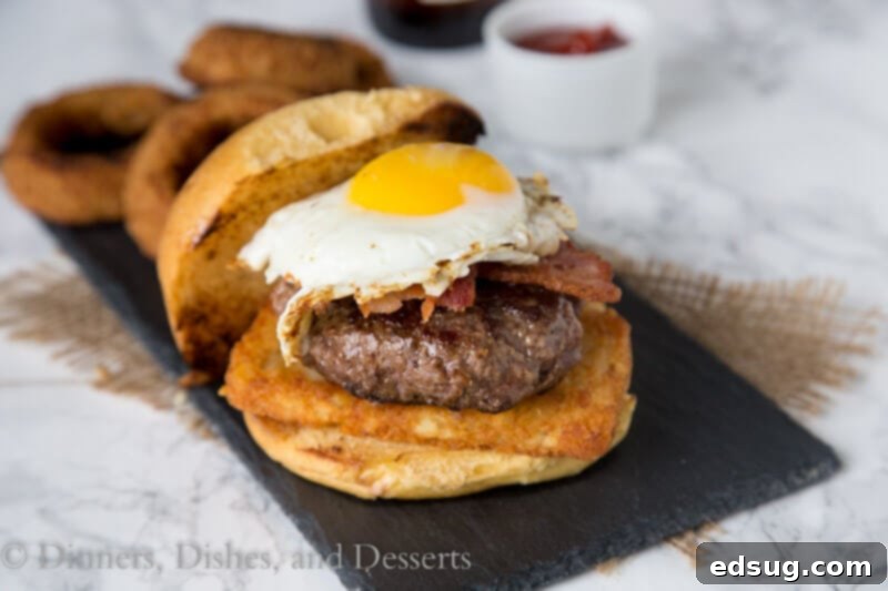 Close-up of a breakfast burger with a fried egg and hash brown on a plate.