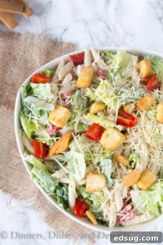 Overhead shot of Caesar pasta salad in a bowl with a serving fork, highlighting its fresh ingredients and inviting texture.