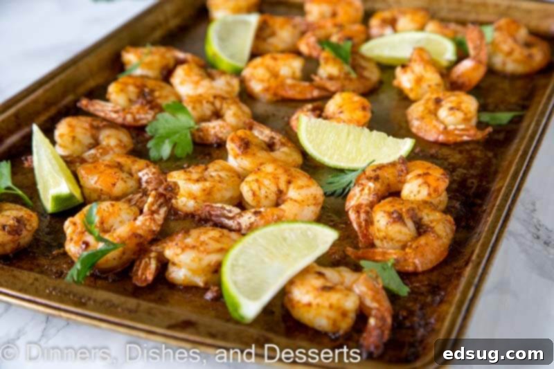 A tray of baked shrimp with fresh lime wedges, ready to be served