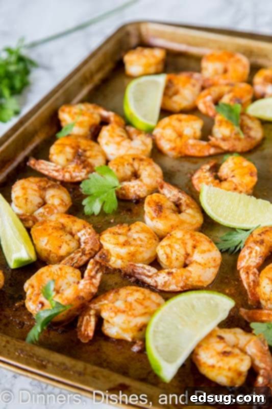 Sheet pan filled with perfectly baked spicy garlic shrimp, garnished with fresh herbs