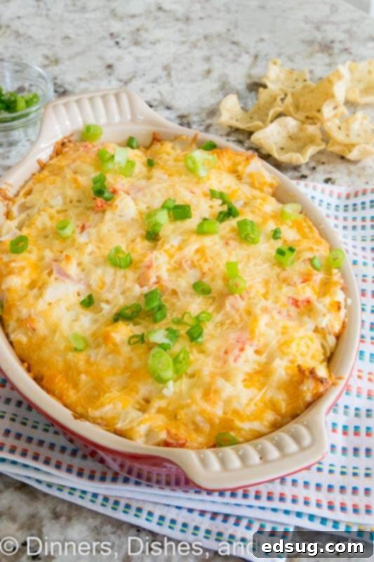 Hot crab dip in a small white baking dish, fresh from the oven and garnished.