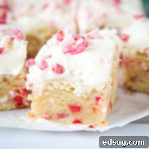 Close up of sliced Peppermint Sugar Cookie Bars on a wooden board, thick and chewy.