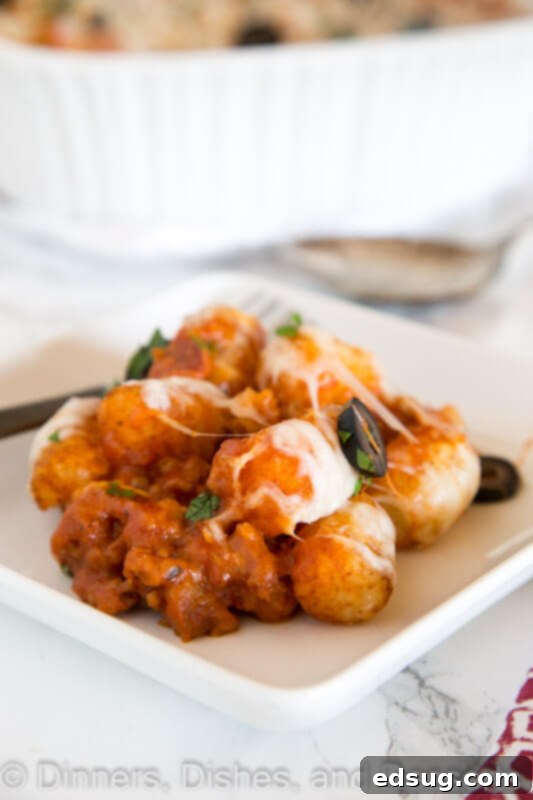 A close-up shot of the bubbling cheese and crispy tater tots in the pizza tater tot casserole.