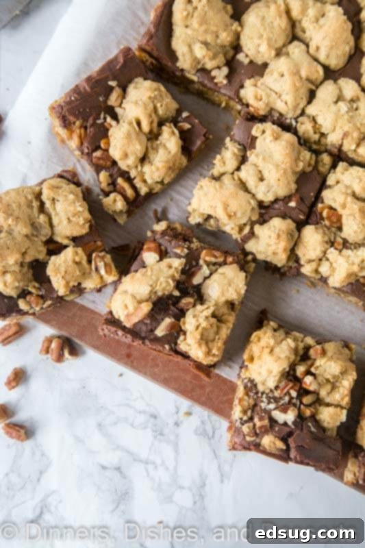 Close-up of freshly baked Fudge Nut Bars on a wooden board, showing the layered texture of cookie, fudge, and nuts.