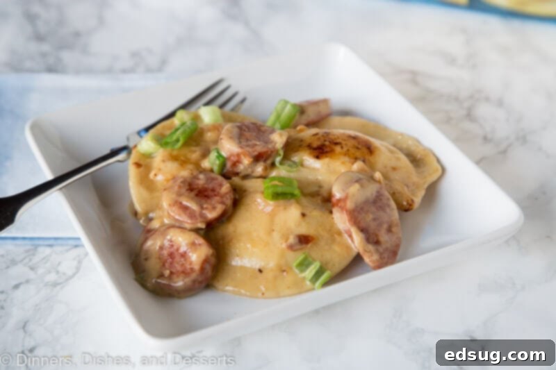 Hearty Sausage and Pierogi Skillet 3 A plate of food with a fork and knife, with Pierogi and Sausage