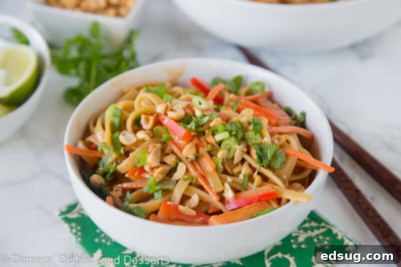 An overhead shot of a prepared bowl of Thai Peanut Noodles and vegetables on a rustic table, ready to be served.