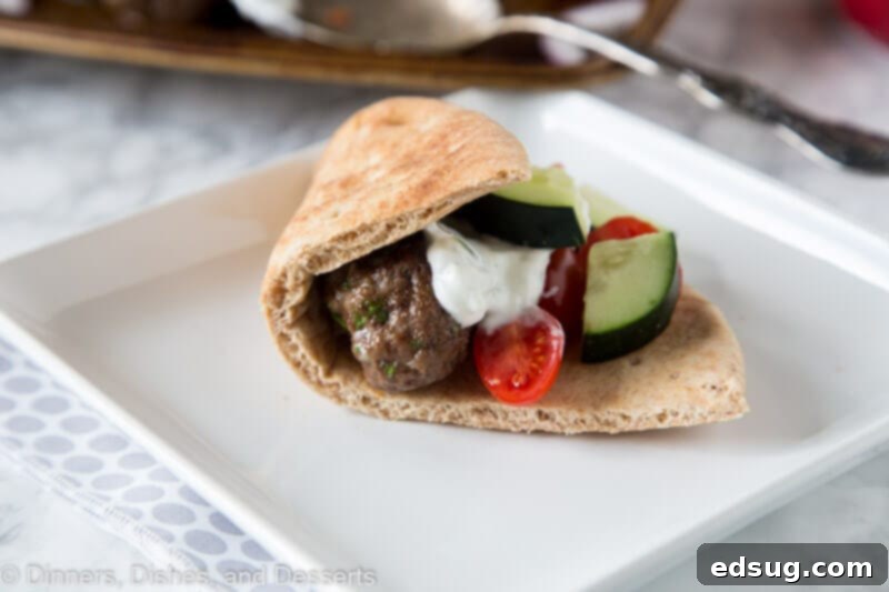 pita filled with meatballs and tzatzki sauce and cucumbers on a plate