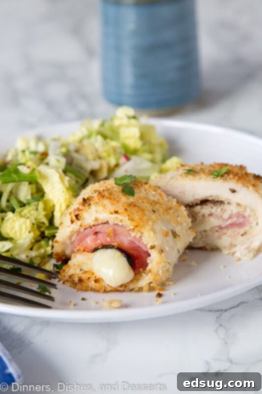 A close-up of a beautifully set table with sliced Crispy Chicken Cordon Bleu, served with a vibrant green salad, ready for a meal.