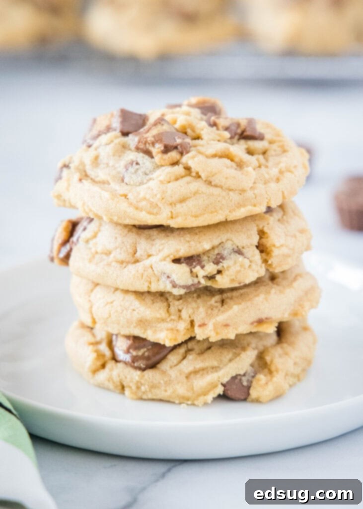 Stacked Reese's Peanut Butter Cookies on a plate, showcasing their soft texture and visible chocolate chips and peanut butter cup pieces.