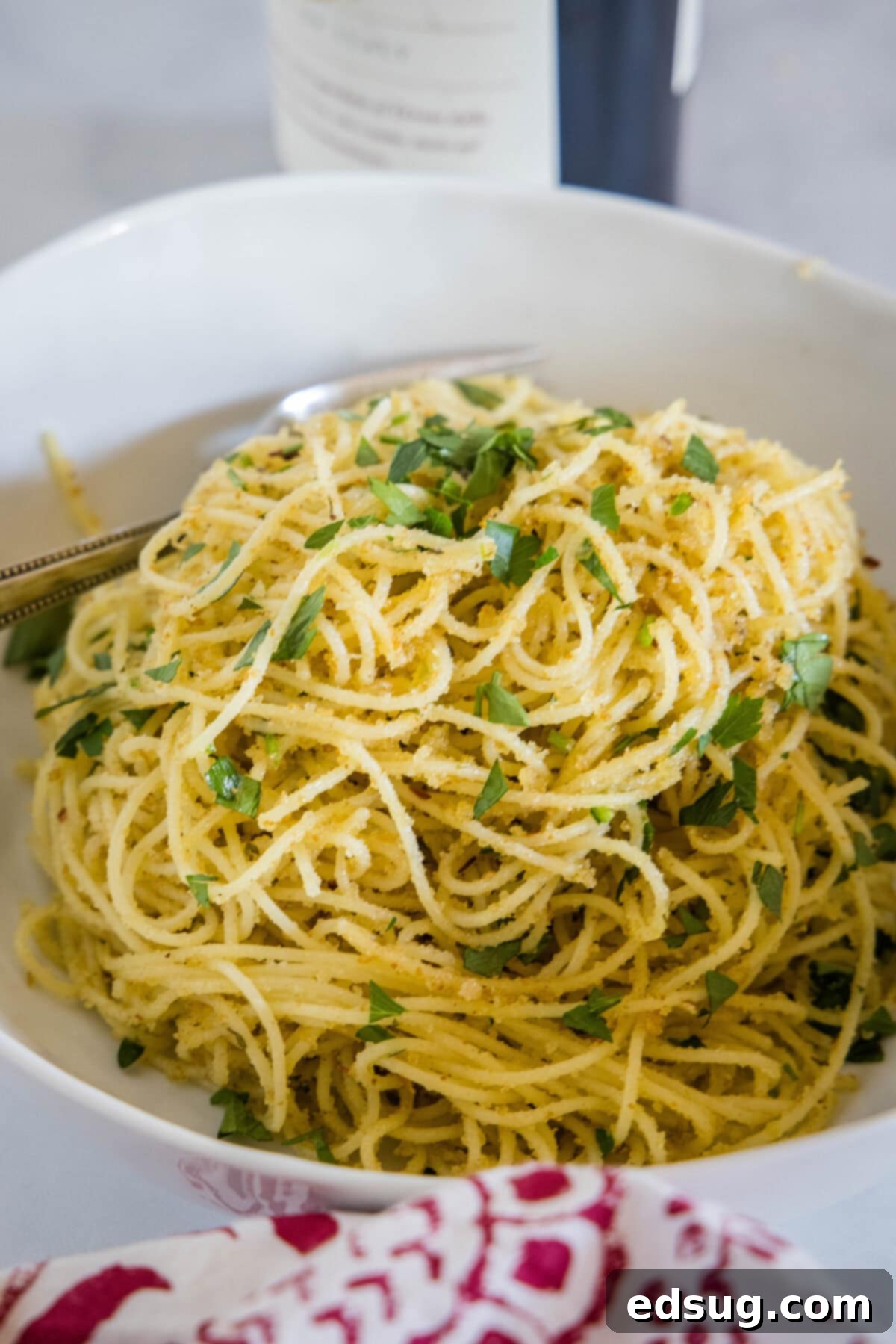 Easy Breadcrumb Pasta Recipe A beautiful white bowl filled with golden pasta with breadcrumbs, garnished with fresh parsley.