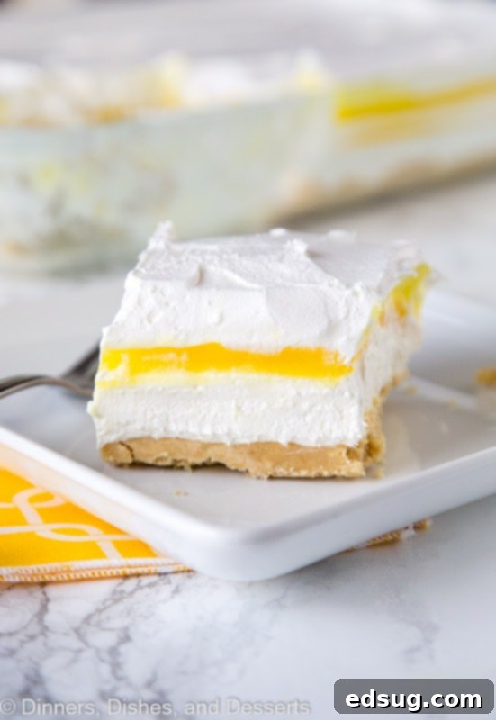 A second view of the lemon lasagna dessert on a plate, highlighting the smooth, creamy layers and the vibrant yellow of the lemon pudding.