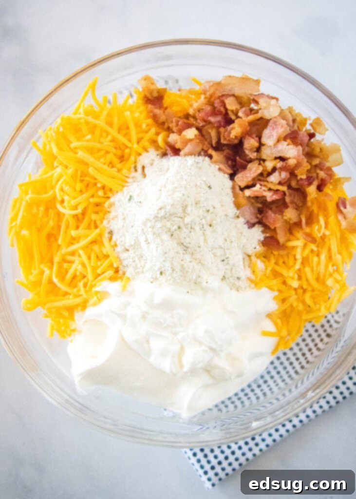 Mixing together the creamy base ingredients for bacon cheddar ranch dip in a large bowl, showing a smooth consistency.