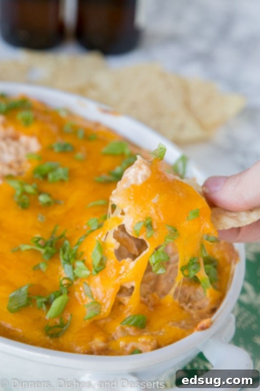 Another shot of a chip scooping up the creamy, cheesy barbecue chicken dip, emphasizing its readiness to be enjoyed.